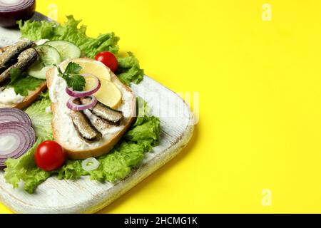 Brett mit Sandwiches mit Sprossen auf gelbem Hintergrund Stockfoto