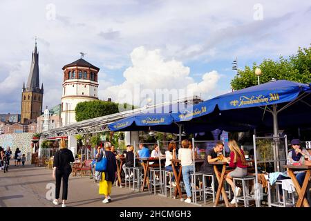 Die beliebte Touristenattraktion Rheinpromenade in Düsseldorf/Deutschland mit Menschen, die im Restaurant im Freien sitzen. Stockfoto