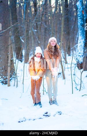 Zwei Mädchen im Teenageralter, die an einem verschneiten Wintertag im Wald mit Schnee spielen. Schnee-Spiele. Winterurlaub. Stockfoto