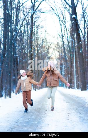 Zwei Mädchen im Teenageralter, die an einem verschneiten Wintertag im Wald mit Schnee spielen. Schnee-Spiele. Winterurlaub. Stockfoto