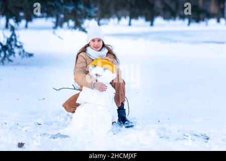 Nettes kleines Teenager-Mädchen mit Spaß spielen machen Schneemann im verschneiten Winterwald. Schnee-Spiele. Winterurlaub. Stockfoto