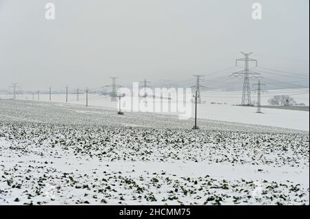 Hochspannungsmasten in der Winterlandschaft mit Schnee. Teure Heizung im Winter und steigende Strompreise in Europa. Stockfoto