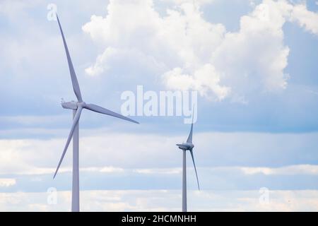 Zwei Windturbinen drehen sich an einem bewölkten und sonnigen Tag, Lincolnshire, Großbritannien, langsam in die Luft Stockfoto