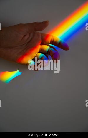 Regenbogenstrahl auf der Hand einer Frau. Stockfoto