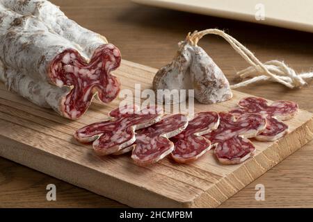 In Scheiben geschnittene französische, handgemachte Trockenwurst, Saucisson sec, auf einem hölzernen Schneidebrett Stockfoto