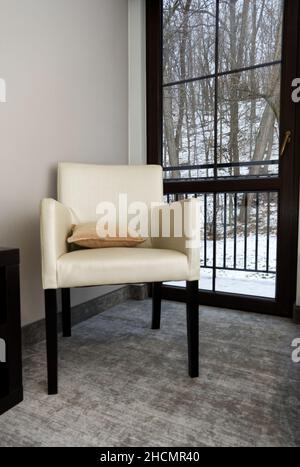 Bequemer Stuhl am Fenster in einem gemütlichen Zimmer im Winter - vertikaler Blick Stockfoto