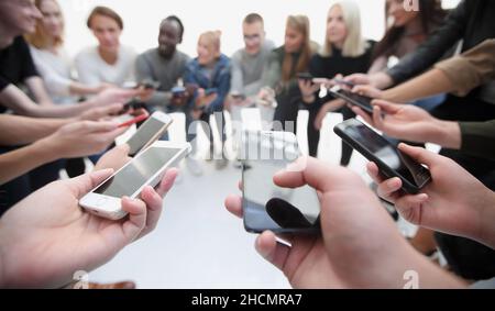 Gruppen junger Menschen, die Nachrichten auf ihrem Smartphone lesen Stockfoto