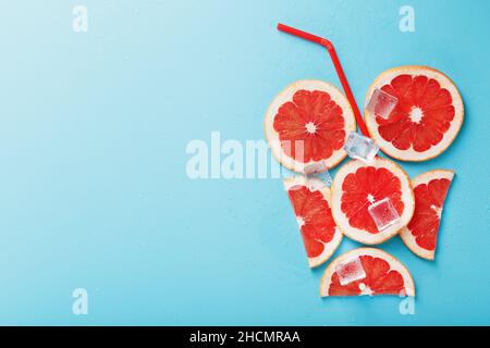 Eine Komposition aus Grapefruitscheiben und Eiswürfeln mit blauem Hintergrund in Form eines erfrischenden Getränks. Draufsicht, freier Platz Stockfoto