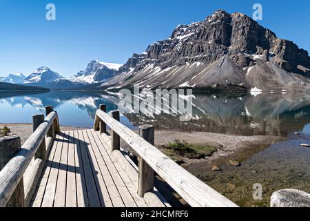 Fußgängerbrücke am Bow Lake entlang des Icefields Parkway im Banff National Park in Alberta, Kanada. Bow Lake entsteht aus der Gletscherschmelze der Eisfelder Crowfoot Glacier und Wapta. Stockfoto