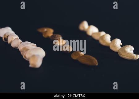 Cashewnüsse, Pistazien und Mandel, schöne Tapete mit auf schwarzem Hintergrund Stockfoto