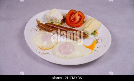 Nahaufnahme von Wurst, Käse, Rührei und Tomaten auf einem weißen Teller Stockfoto