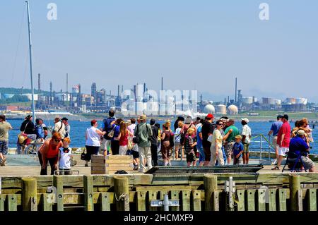 Halifax, Kanada - 19. Juli 2009: Eine Menschenmenge trifft sich an der Halifax Waterfront, einem beliebten Touristenziel. In ist eine Ölraffinerie in Dartmouth zu sehen Stockfoto