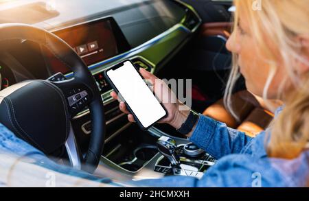 Frau hält schwarzes Handy in den Händen mit leerem Desktop-Bildschirm, während das Auto im Sommer in der Stadt fährt, Mockup-Bild Stockfoto