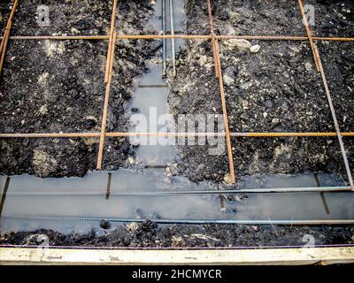 Die Baustelle wurde über einen mit Regenwasser gefüllten Graben aufgehängt. Stockfoto