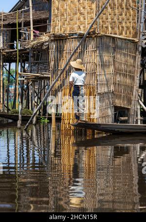 Angehörige der ethnischen Minderheit Intha Frau in einem kleinen Boot vor dem Pfahlhaus am Inle-See, Shan State, Burma, Myanamar, Südostasien Stockfoto