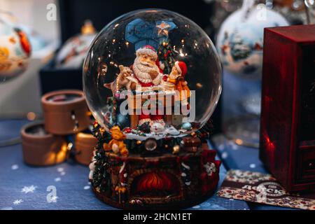 Magische Kristallkugel mit einem Spielzeug Weihnachtsmann und Elf. Neujahrsgeschenk und niedliches Weihnachtsgeschenk. Festliche magische Details Stockfoto