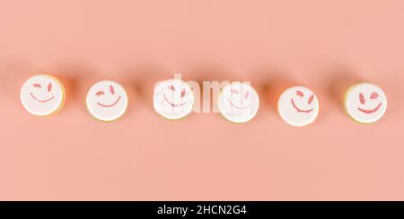 Reihe von runden lustigen Süßigkeiten mit lächelnden Emoticons auf ihnen. Isoliert auf beige mit Beschneidungspfad Stockfoto