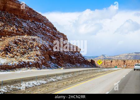 Die schneebedeckte rote Felsenkette hinter der Wüstenlandschaft entlang der I-40 Autobahn in New Mexico Stockfoto