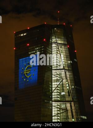 30. Dezember 2021, Hessen, Frankfurt/Main: Während eines Testlaufs wird das Euro-Symbol auf die Südfassade des Hauptquartiers der Europäischen Zentralbank (EZB) im Frankfurter Ostende projiziert. Vor 20 Jahren wurde am Silvesterabend in zwölf EU-Ländern die gemeinsame europäische Währung, der Euro, eingeführt. Für Deutschland bedeutete dies, Auf Wiedersehen zur D-Mark zu sagen. Vom 31. Dezember 2021 bis zum 9. Januar 2022 wird die Fassade der EZB in den Abendstunden beleuchtet. Foto: Arne Dedert/dpa Stockfoto