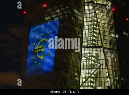 30. Dezember 2021, Hessen, Frankfurt/Main: Während eines Testlaufs wird eine Projektion auf die Südfassade des Hauptquartiers der Europäischen Zentralbank (EZB) im Osten Frankfurts projiziert. Vor 20 Jahren wurde am Silvesterabend in zwölf EU-Ländern die einheitliche europäische Währung, der Euro, eingeführt. Für Deutschland bedeutete das, Auf Wiedersehen zur Deutschen Mark zu sagen. Vom 31. Dezember 2021 bis zum 9. Januar 2022 wird die Fassade der EZB in den Abendstunden beleuchtet. Foto: Arne Dedert/dpa Stockfoto