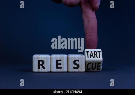 Symbol für Rettung und Neustart. Geschäftsmann dreht einen Holzwürfel und ändert das Wort Rescue, um neu zu starten. Schöner grauer Tisch, grauer Hintergrund. Business und Stockfoto