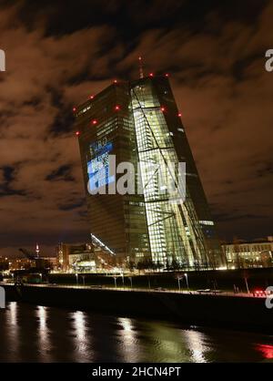 30. Dezember 2021, Hessen, Frankfurt/Main: Bei einem Testlauf wird der Satz "der Euro gehört uns allen" auf die Südfassade des Hauptquartiers der Europäischen Zentralbank (EZB) im Frankfurter Ostende projiziert. Vor 20 Jahren wurde am Silvesterabend in zwölf EU-Ländern die einheitliche europäische Währung, der Euro, eingeführt. Für Deutschland bedeutete dies, Auf Wiedersehen zur D-Mark zu sagen. Vom 31. Dezember 2021 bis zum 9. Januar 2022 wird die Fassade der EZB in den Abendstunden beleuchtet. Foto: Arne Dedert/dpa Stockfoto