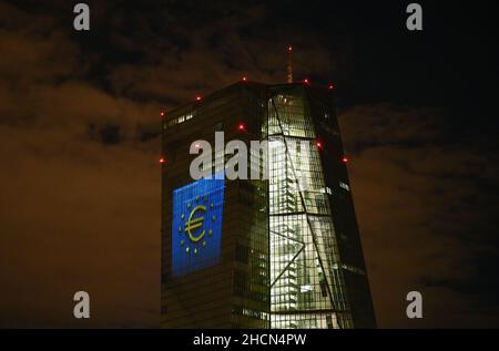 30. Dezember 2021, Hessen, Frankfurt/Main: Während eines Testlaufs wird das Euro-Symbol auf die Südfassade des Hauptquartiers der Europäischen Zentralbank (EZB) im Frankfurter Ostende projiziert. Vor 20 Jahren wurde am Silvesterabend in zwölf EU-Ländern die gemeinsame europäische Währung, der Euro, eingeführt. Für Deutschland bedeutete dies, Auf Wiedersehen zur D-Mark zu sagen. Vom 31. Dezember 2021 bis zum 9. Januar 2022 wird die Fassade der EZB in den Abendstunden beleuchtet. Foto: Arne Dedert/dpa Stockfoto