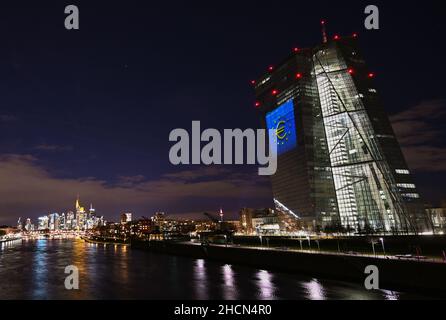 30. Dezember 2021, Hessen, Frankfurt/Main: Während eines Testlaufs wird das Euro-Symbol auf die Südfassade des Hauptquartiers der Europäischen Zentralbank (EZB) im Frankfurter Ostende projiziert. Vor 20 Jahren wurde am Silvesterabend in zwölf EU-Ländern die gemeinsame europäische Währung, der Euro, eingeführt. Für Deutschland bedeutete dies, Auf Wiedersehen zur D-Mark zu sagen. Vom 31. Dezember 2021 bis zum 9. Januar 2022 wird die Fassade der EZB in den Abendstunden beleuchtet. Foto: Arne Dedert/dpa Stockfoto