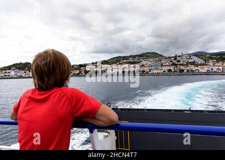 Kind blickt auf Horta auf einer Fähre von Faial nach Pico. Azoren, Portugal. Passagiere im obersten Deck der Fähre. Stockfoto