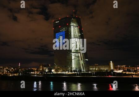 30. Dezember 2021, Hessen, Frankfurt/Main: Während eines Testlaufs wird das Euro-Symbol auf die Südfassade des Hauptquartiers der Europäischen Zentralbank (EZB) im Frankfurter Ostende projiziert. Vor 20 Jahren wurde am Silvesterabend in zwölf EU-Ländern die gemeinsame europäische Währung, der Euro, eingeführt. Für Deutschland bedeutete dies, Auf Wiedersehen zur D-Mark zu sagen. Vom 31. Dezember 2021 bis zum 9. Januar 2022 wird die Fassade der EZB in den Abendstunden beleuchtet. Foto: Arne Dedert/dpa Stockfoto