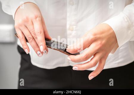 Gepflegte Hände und Werkzeuge für eine Maniküre. Hände des Manikuristen nehmen das Instrument für eine Maniküre aus dem Lederetui in einem Nagelstudio ab Stockfoto