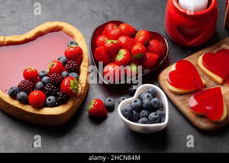 Herzförmiger süßer Kuchen mit Beeren und Keksen. Grußkarte zum Valentinstag Stockfoto