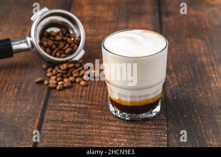 Cortado-Kaffee mit Kaffeebohnen daneben. Traditioneller Kaffee in Spanien. Stockfoto