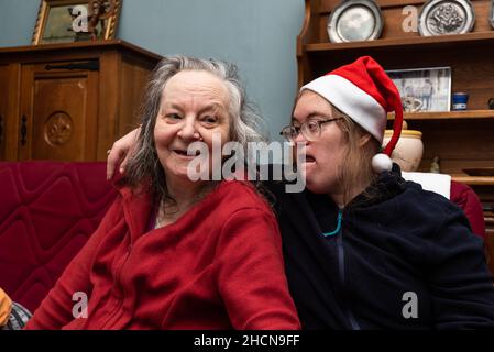 Glückliche 83-jährige ältere Frau und ihre 39-jährige Tochter mit dem Down-Syndrom während der Weihnachtszeit Stockfoto