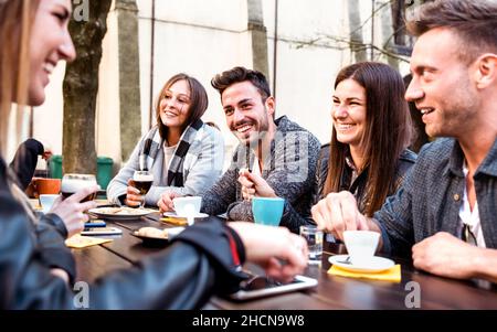 Leute, die heiße Getränke im Kaffeerestaurant Dehor probieren - Milenial-Freunde, die im Bürgersteig-Café miteinander reden und Spaß haben - Life Style-Konzept Stockfoto