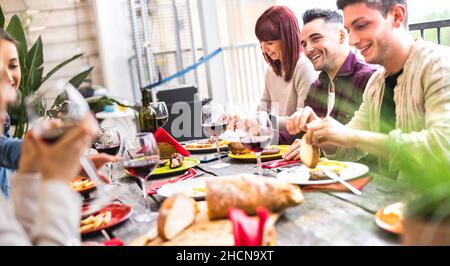 Glückliche Menschen trinken zusammen Wein auf der Dachparty in der Freiluftvilla - Junge Freunde essen Essen im Restaurant Patio - Coole Freundschaft Konzept Stockfoto