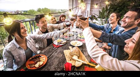 Junge Leute haben Spaß beim gemeinsamen Toasten von Rotwein bei der Dinner Party in der Outdoor Villa - glückliche Freunde essen bbq-Essen auf der Restaurantterrasse Stockfoto