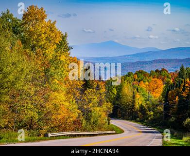 Eine Straße schlängelt sich durch die herbstliche Laublandschaft in der Landschaft von Vermont Stockfoto