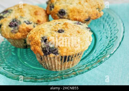Hausgemachte Blaubeer-Muffins auf einem blaublütenblauen Glasplatte. Stockfoto