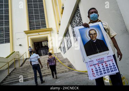 San Salvador, El Salvador. 30th Dez 2021. Ein Mann verkauft 2022 Kalender außerhalb der Kathedrale von San Salvador, während die Leute in der Innenstadt für den Silvesterabend einkaufen. Kredit: SOPA Images Limited/Alamy Live Nachrichten Stockfoto