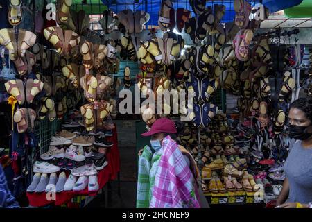 San Salvador, El Salvador. 30th Dez 2021. Frauen sahen, wie sie an einem Schuhgeschäft am Straßenmarkt vorbeigingen, während die Leute am Silvesterabend in der Innenstadt einkaufen. Kredit: SOPA Images Limited/Alamy Live Nachrichten Stockfoto