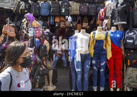 San Salvador, El Salvador. 30th Dez 2021. Eine Frau geht am Bekleidungsgeschäft am Straßenmarkt vorbei, während die Leute am Silvesterabend in der Innenstadt einkaufen. Kredit: SOPA Images Limited/Alamy Live Nachrichten Stockfoto