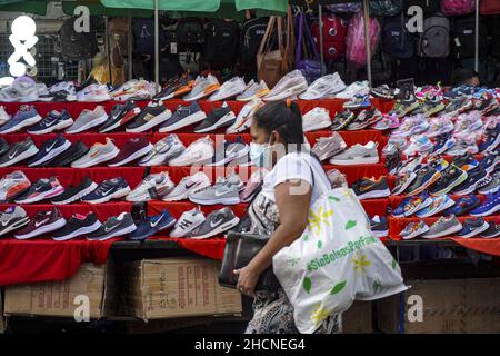 San Salvador, El Salvador. 30th Dez 2021. Eine Frau geht an einem Schuhgeschäft am Straßenmarkt vorbei, während die Leute in der Innenstadt Silvester einkaufen. Kredit: SOPA Images Limited/Alamy Live Nachrichten Stockfoto