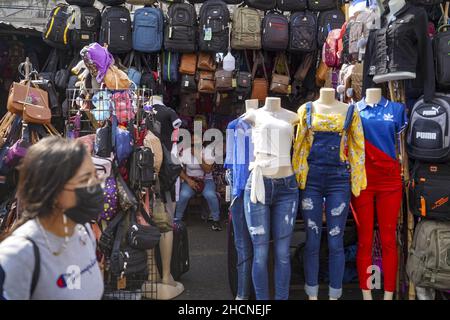San Salvador, El Salvador. 30th Dez 2021. Eine Frau geht am Bekleidungsgeschäft am Straßenmarkt vorbei, während die Leute am Silvesterabend in der Innenstadt einkaufen. (Foto von Camilo Freedman/SOPA Images/Sipa USA) Quelle: SIPA USA/Alamy Live News Stockfoto