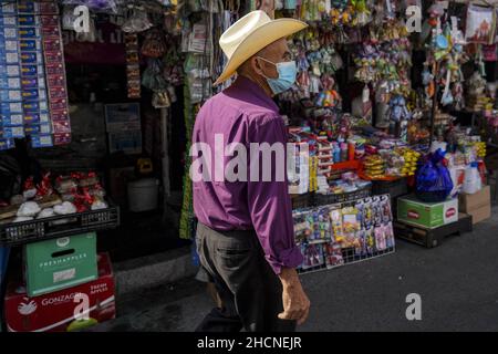San Salvador, El Salvador. 30th Dez 2021. Ein Mann mit Schutzmaske sah, wie er an Geschäften auf dem lokalen Markt vorbeiging, als Leute Silvester in der Innenstadt einkaufen. (Foto von Camilo Freedman/SOPA Images/Sipa USA) Quelle: SIPA USA/Alamy Live News Stockfoto