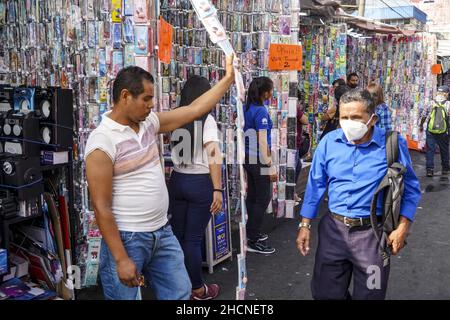 San Salvador, El Salvador. 30th Dez 2021. Ein Mann geht an einem Verkäufer von Handy-Zubehör vorbei, während Leute für einen Silvester in der Innenstadt einkaufen. (Foto von Camilo Freedman/SOPA Images/Sipa USA) Quelle: SIPA USA/Alamy Live News Stockfoto
