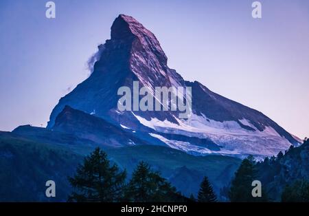 Panoramablick auf den Matterhorn-Gipfel vom Dorf Zermatt aus an einem Sommerabend während der blauen und violetten Stunde, Zermatt, Schweiz Stockfoto