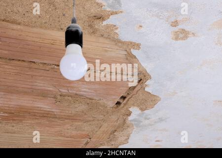 Innenrekonstruktion an der verfallenen alten Decke und Hängelampe. Reparieren gealterte Architektur Texturdesign. Stockfoto