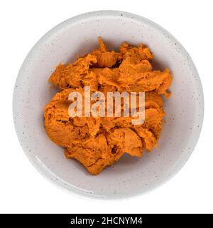 Geschmorter Kürbis auf weißem Keramikbecher isoliert auf weißem Hintergrund. Stockfoto