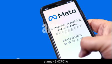Menlo Park, CA, USA, Oktober 28 2021: Hand hält ein Telefon mit der Meta Mobile App auf dem Bildschirm auf blauem Hintergrund. Meta ist ein Technologieunternehmen t Stockfoto